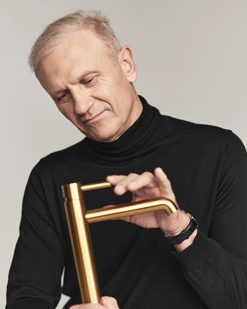 Janusz Langner holding a gold Y collection basin mixer