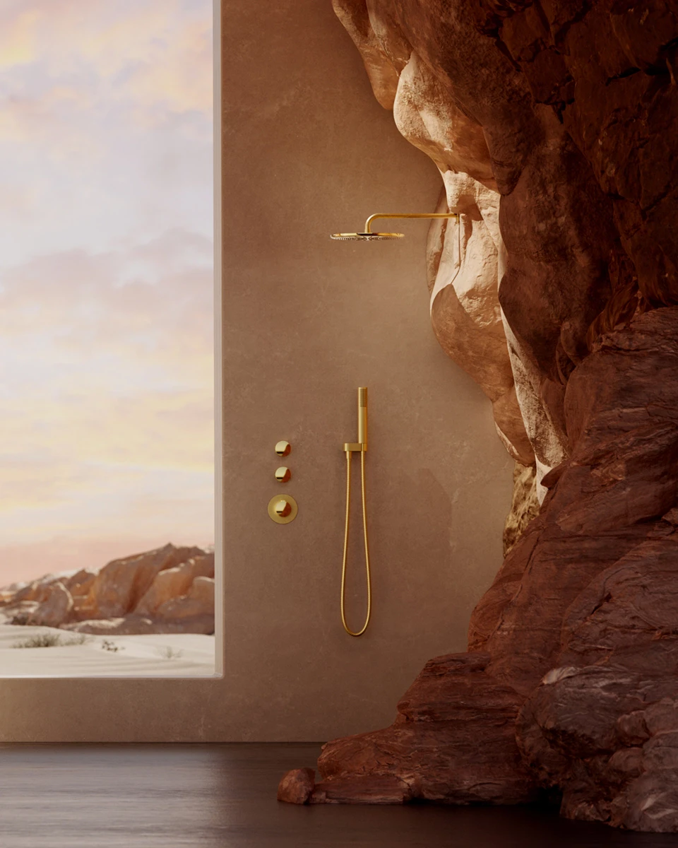 Gold BEYOND shower system by a rock wall